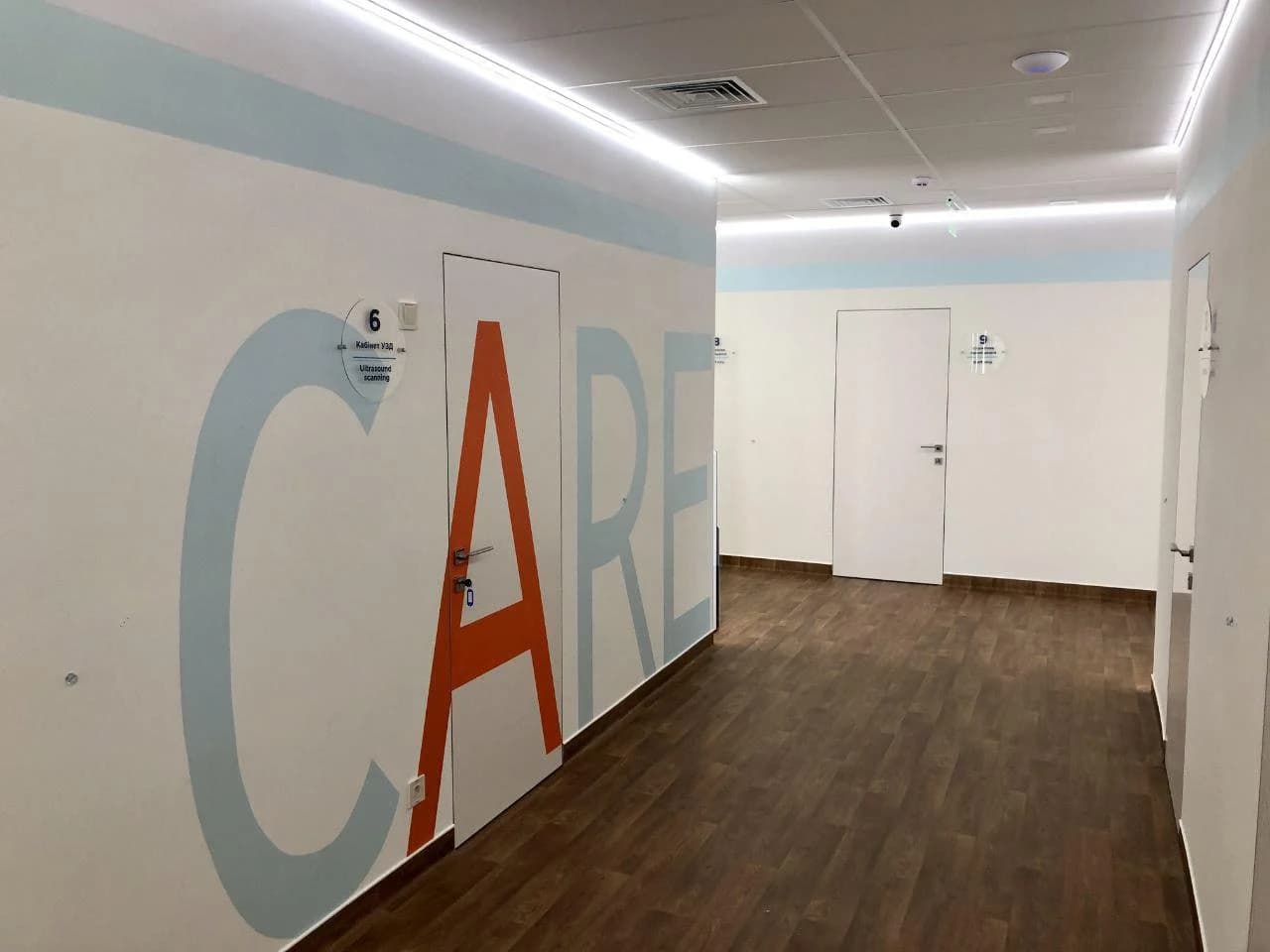 Clinic corridor with CARE wall branding and ultrasound rooms